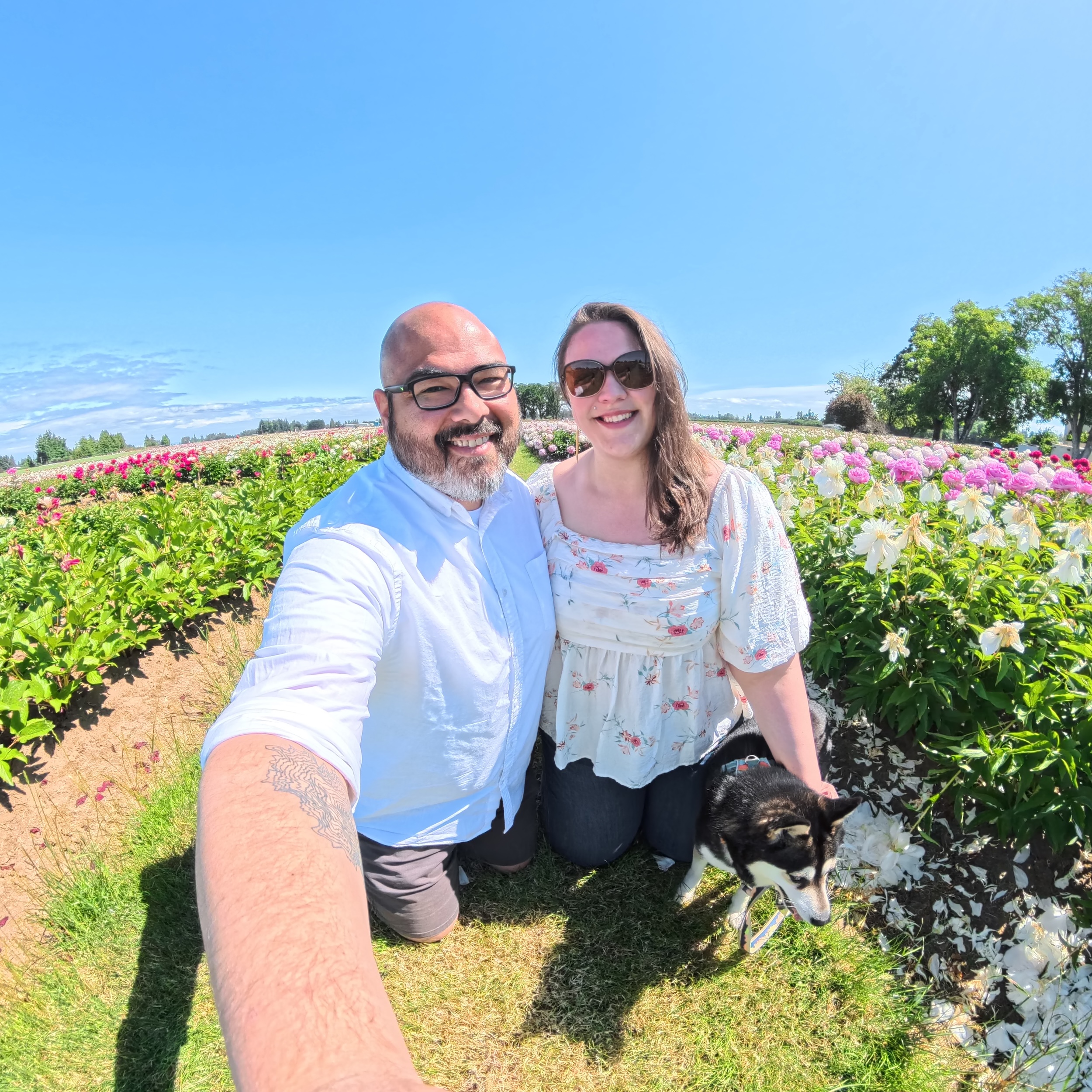 a man, a woman, and a dog, taking a selfie on a sunny day at a peony farm in Oregon